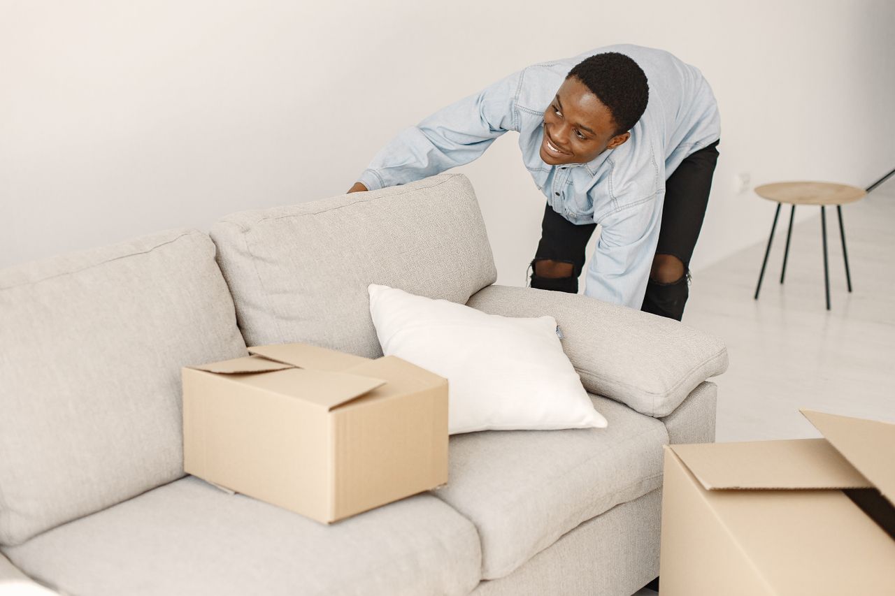 Young man smiling as he organizes cardboard boxes in a contemporary living room.